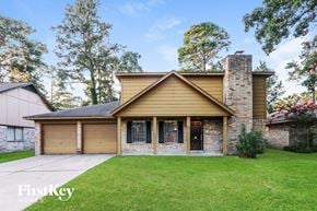 Spring house for rent - A house with a brown roof and a chimney is surrounded by green grass and trees.