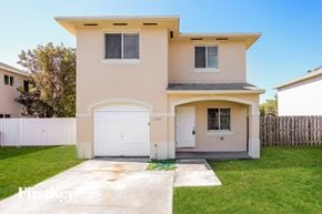 Homestead house for rent - a white house with a white garage door and a lawn