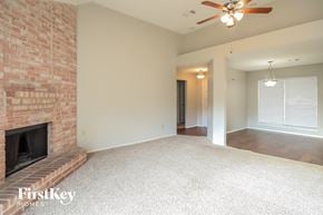 Katy house for rent - an empty living room with a brick fireplace and a ceiling fan