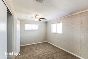 Phoenix house for rent - a bedroom with a ceiling fan and a white brick wall