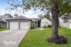 Katy house for rent - a house with a garage and a tree in the yard