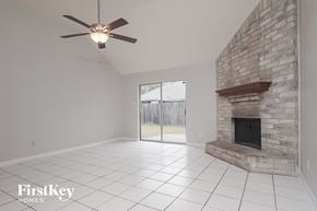 Katy house for rent - an empty living room with a stone fireplace and a ceiling fan