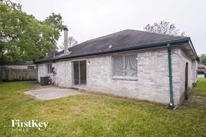 Katy house for rent - the backyard of a small brick house with a yard and grass