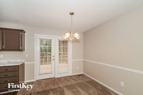Helena house for rent - A room with a brown carpet and a chandelier hanging from the ceiling.