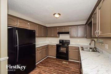 Helena house for rent - A kitchen with a black fridge and wooden floors.