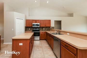 Cape Coral house for rent - a kitchen with wooden cabinets and stainless steel appliances