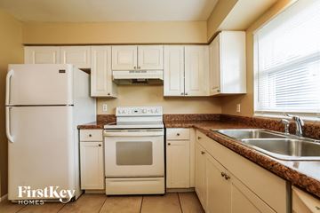 Cape Coral house for rent - a kitchen with white appliances and white cabinets and granite counter tops