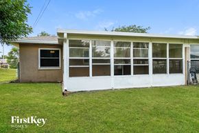 Cape Coral house for rent - the back of a house with a white porch and grass