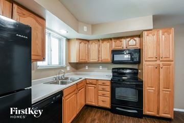 Florissant house for rent - a kitchen with black appliances and wooden cabinets