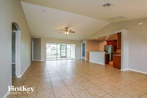 Cape Coral house for rent - A spacious living room with a kitchen in the background.