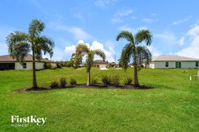 Cape Coral house for rent - A lawn with two palm trees and a house in the background.