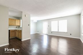 Indianapolis house for rent - an empty living room and kitchen with wood floors and white walls