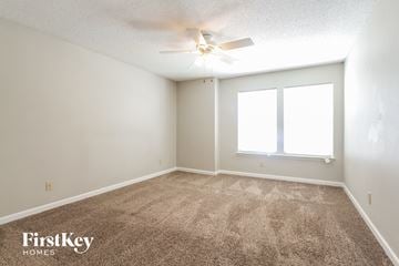 Indianapolis house for rent - a spacious living room with carpet and a ceiling fan