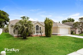 Ocoee house for rent - a house with a lawn and palm trees in front of it