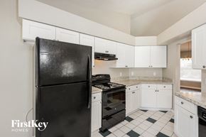 Ocoee house for rent - a kitchen with white cabinets and black appliances and a black refrigerator