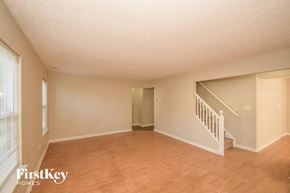 Indianapolis house for rent - A spacious room with wooden floors and a staircase leading to another room.