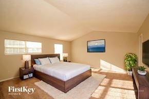 Indianapolis house for rent - A bedroom with a large bed, a painting on the wall, and a potted plant.