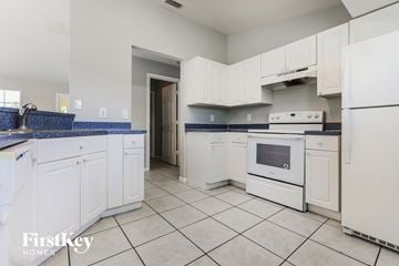 North Port house for rent - a kitchen with white cabinets and white appliances and blue counter tops
