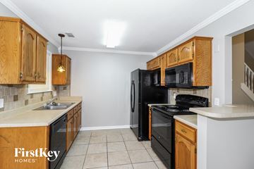 Cordova house for rent - A kitchen with wooden cabinets and black appliances.