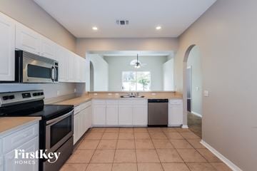 Lakeland house for rent - A kitchen with white cabinets and black appliances.