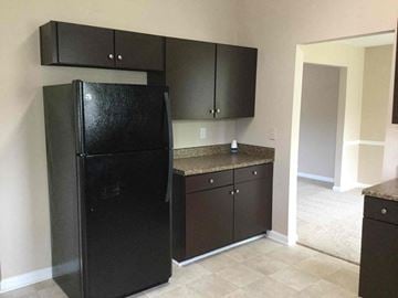 Ellenwood house for rent - a kitchen with black cabinets and a black refrigerator
