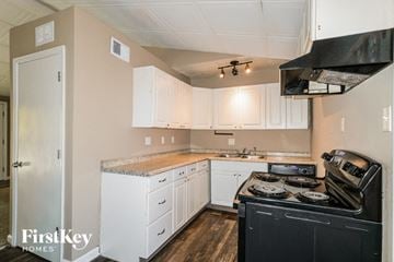 Florissant house for rent - A kitchen with a black stove top oven and white cabinets.