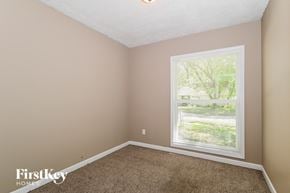 Florissant house for rent - A room with a carpeted floor and a window showing a view of trees and a building outside.