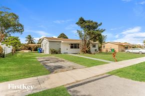 Homestead house for rent - a white house with a lawn and a white car parked in a driveway