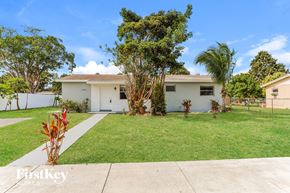 Homestead house for rent - a white house with a lawn and palm trees