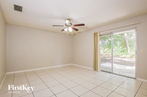 Deltona house for rent - A room with a ceiling fan and sliding glass doors.