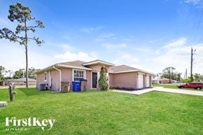 Lehigh Acres house for rent - A house with a blue trash bin and a red car in the driveway.