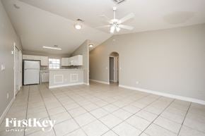 Lehigh Acres house for rent - A spacious empty room with a ceiling fan and a kitchen area in the background.