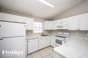 Lehigh Acres house for rent - A kitchen with white cabinets and appliances, with a FirstKey Homes logo on the bottom left.
