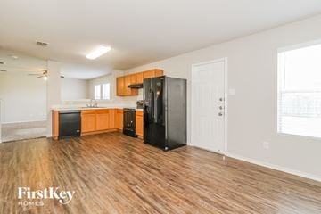 Royse City house for rent - a kitchen with wood flooring and a black refrigerator