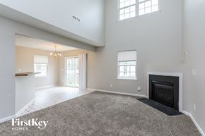Raleigh house for rent - A spacious living room with a fireplace and a carpeted floor.