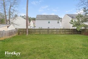 Raleigh house for rent - A grassy yard with a fence and houses in the background.
