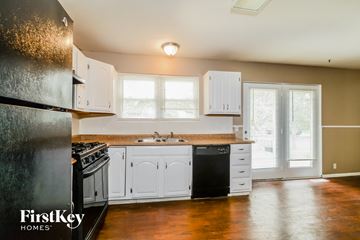 Florissant house for rent - a kitchen with white cabinets and a sink and a refrigerator