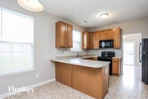 Raleigh house for rent - a kitchen with wooden cabinets and a white counter top