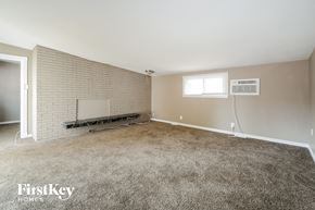 Florissant house for rent - a living room with carpet and a brick wall and a window