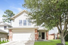 Houston house for rent - a white house with a white garage door and a tree