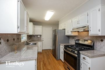 Marietta house for rent - a kitchen with white cabinets and stainless steel appliances