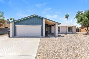 Phoenix house for rent - a blue and white house with a garage door and a gravel driveway