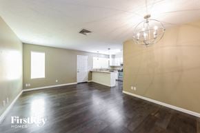 Phoenix house for rent - an empty living room and kitchen with wood floors and a chandelier