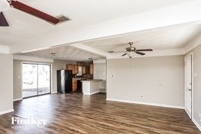 Plano house for rent - A spacious room with wooden floors and a ceiling fan.
