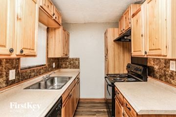 Plano house for rent - A kitchen with wooden cabinets and a stove top oven.