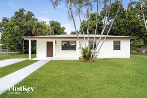 Miami Gardens house for rent - a small white house with a lawn and palm tree
