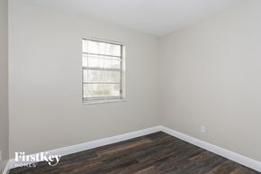 Miami Gardens house for rent - a bedroom with white walls and wood floors and a window