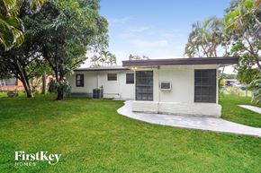 Miami Gardens house for rent - a small white house with a grassy yard and palm trees