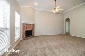 Denton house for rent - a living room with a brick fireplace and a ceiling fan