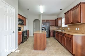 Denton house for rent - a large kitchen with wooden cabinets and black appliances